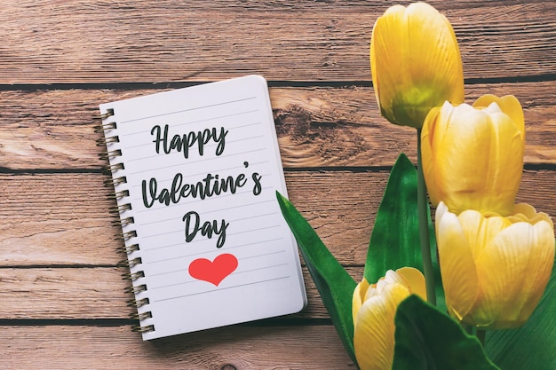 Gelukkige Valentijnsdaggroet op blocnote met gele tulpenbloem