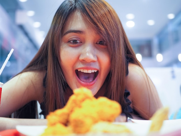 Foto gelukkige verbaasde jonge vrouw die naar eten kijkt in een restaurant