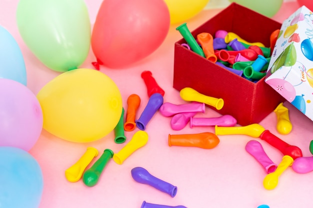 Gelukkige verjaardag-concept. gekleurde ballonnen en geschenkdoos op een roze tafel, bovenaanzicht lay-out