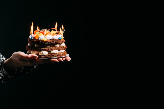 Gelukkige verjaardag Feestelijke bakkerij Feestviering Reclame achtergrond Elegante vrouwelijke handen met vakantie cake kaarslichten geïsoleerde zwarte kopie ruimte