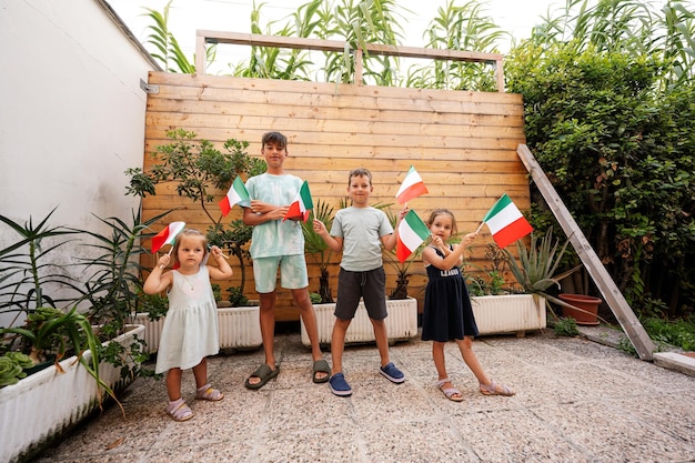 Gelukkige vier kinderen met Italiaanse vlaggen die de Dag van de Republiek van Italië vieren