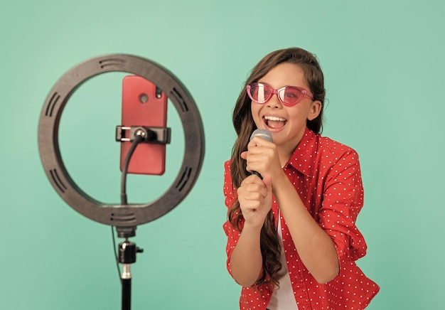 Foto gelukkige vlogger met microfoon die videoblog maakt op smartphone-bloglamplamp