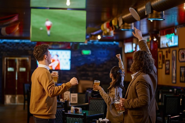 Gelukkige voetbalfans juichen bier drinken en voetbalwedstrijd kijken