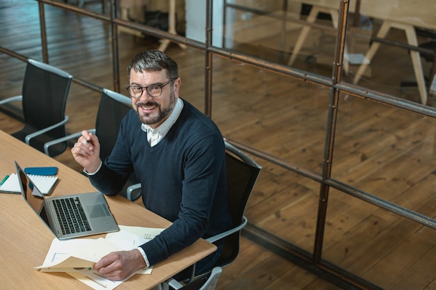 Foto gelukkige volwassen man aan het werk met rapport op kantoor