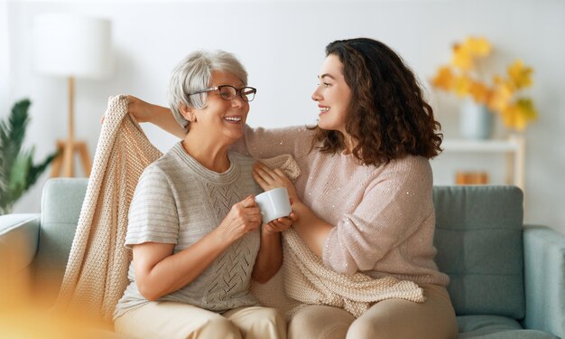 Gelukkige volwassen vrouw en haar oudere moeder thuis