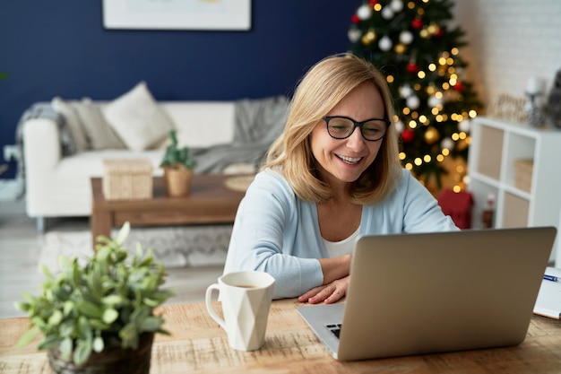 Gelukkige volwassen vrouw met videoconferentie tijdens Kerstmis thuis