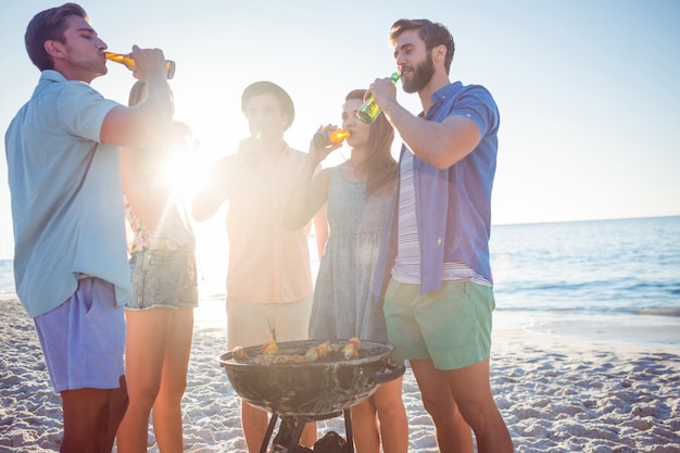 Gelukkige vrienden die barbecue doen en bier drinken