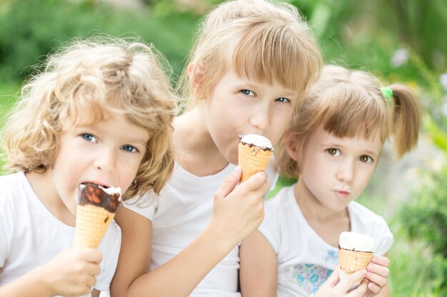 Gelukkige vrienden die buiten ijs eten in het lentepark