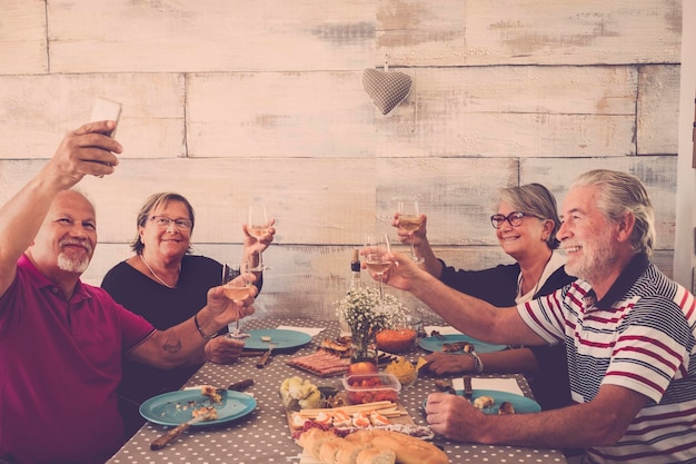 Gelukkige vrienden die drinken terwijl ze een selfie maken aan tafel.