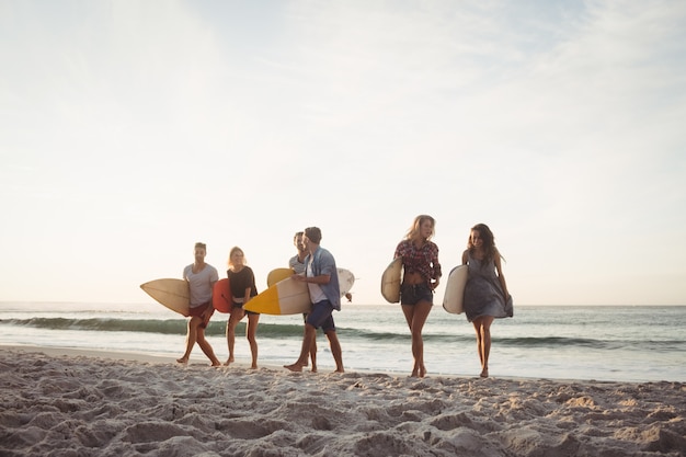 Gelukkige vrienden die met surfplanken lopen