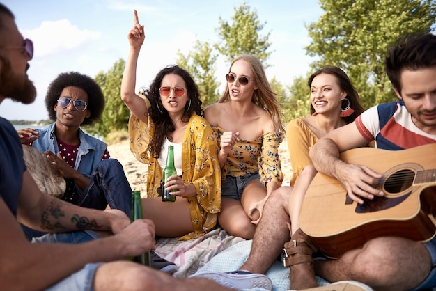 Gelukkige vrienden die plezier hebben op het strand met muziekinstrumenten