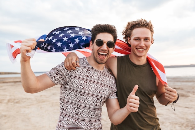 Gelukkige vrienden die tijd doorbrengen op het strand, met Amerikaanse vlag
