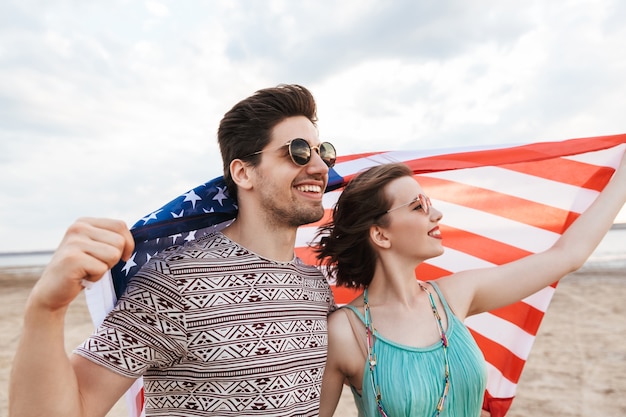 Gelukkige vrienden die tijd doorbrengen op het strand, met Amerikaanse vlag