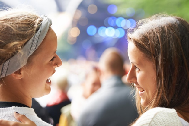 Gelukkige vrienden en vrouwen op een muziekfestival concert of feest voor het sociale leven opgewonden en praten over rave of techno Mensen publiek of menigte van achteren op een carnavalsevenement en bokeh op een podium