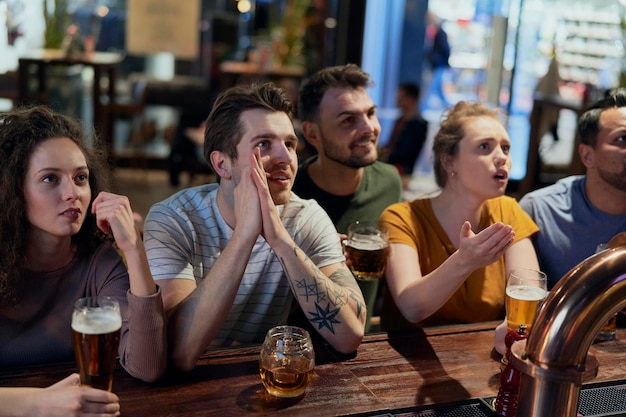 Foto gelukkige vrienden kijken naar een voetbalwedstrijd in de bar.