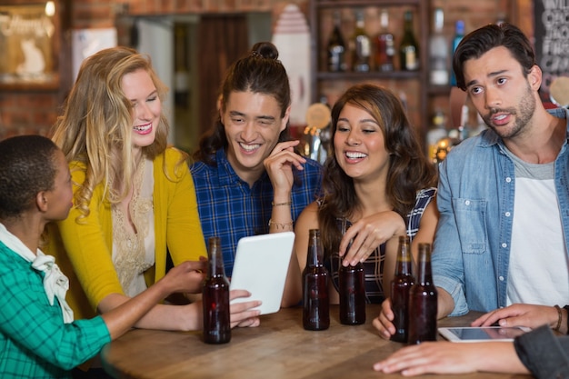 Gelukkige vrienden met bierflesjes met behulp van digitale tablet