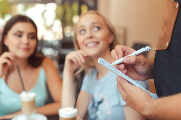 Gelukkige vrienden praten op zoek elkaar zitten in de tabel van een bar met de ober