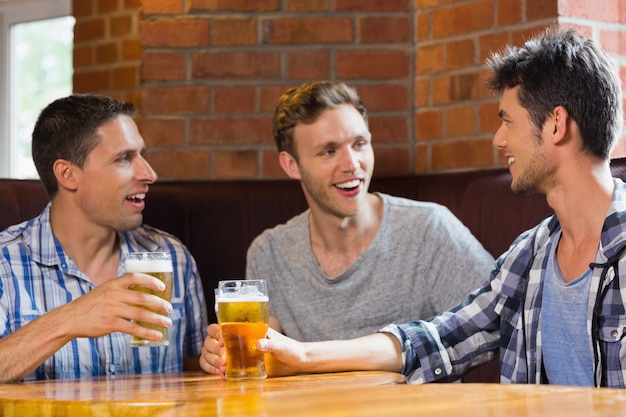 Gelukkige vrienden roosteren met pinten bier