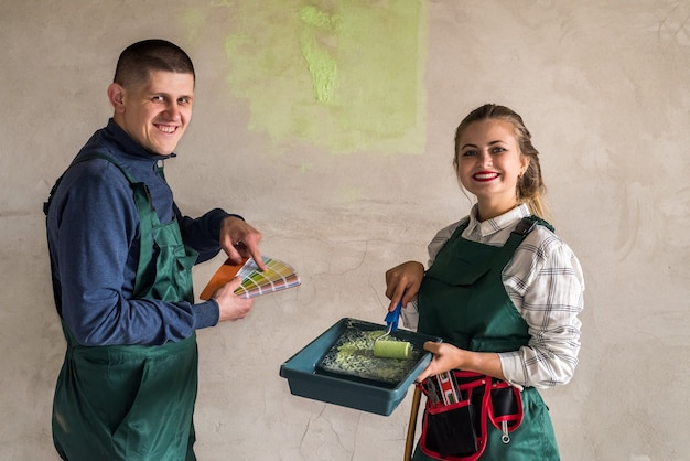 Gelukkige vrienden schilderen muren in groene kleur