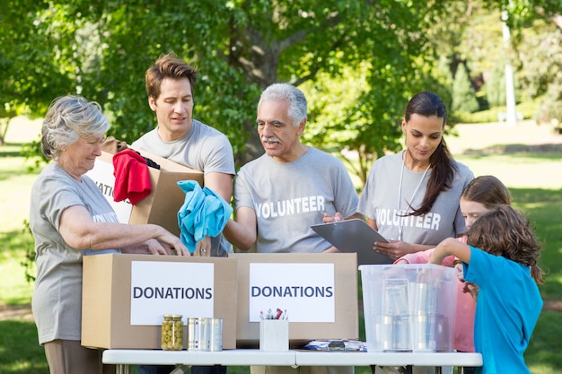 Gelukkige vrijwilligersfamilie die schenkingenmaterialen scheidt
