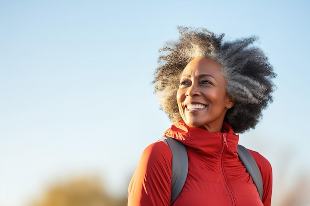 Gelukkige vrolijke Afro-Amerikaanse oudere vrouw met rugzak en actieve levensstijl positieve volwassen dame in herfstkleding wandelen in de buitenlucht kopiëren ruimte