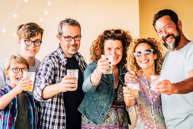 Gelukkige vrolijke groep blanke mensen van gemengde generatie en leeftijden hebben plezier samen rammelend en roosteren om samen te vieren - concept van feest en vriendschap voor volwassenen en tieners