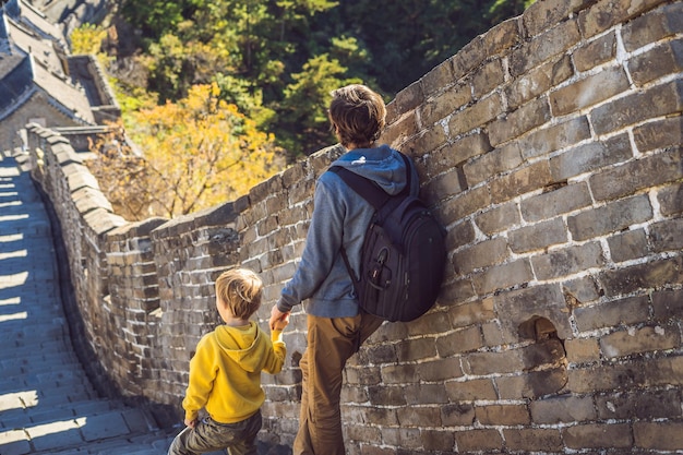 Gelukkige vrolijke vrolijke toeristen vader en zoon bij de grote muur van China die plezier hebben op reizen glimlachend