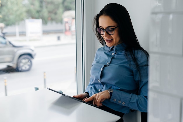 Gelukkige vrouw aan tafel zitten en kijken naar tablet