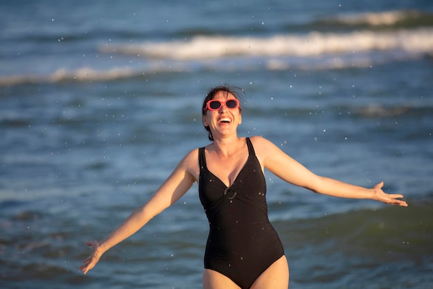 Gelukkige vrouw aan zee Vrouw in een zwembroek spat water