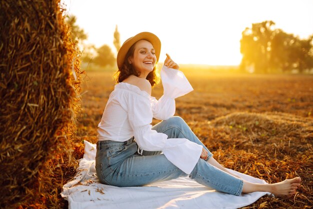 Gelukkige vrouw bij hooiberg bij zonsondergang Mode concept Natuur vakantie ontspanning en levensstijl