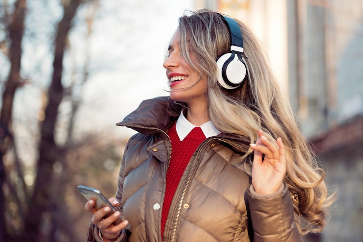 Foto gelukkige vrouw die aan muziek op draadloze hoofdtelefoons luistert