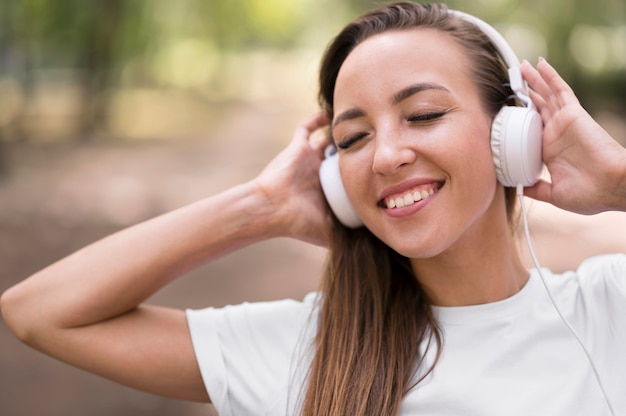 Gelukkige vrouw die aan muziek op haar hoofdtelefoons luistert