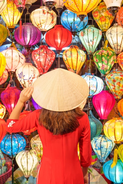 Gelukkige vrouw die ao dai vietnamese jurk draagt met kleurrijke lantaarns reiziger die bezienswaardigheden bezoekt in hoi an oude stad in centraal vietnamlandmark voor toeristische attractiesvietnam en zuidoost-reisconcept