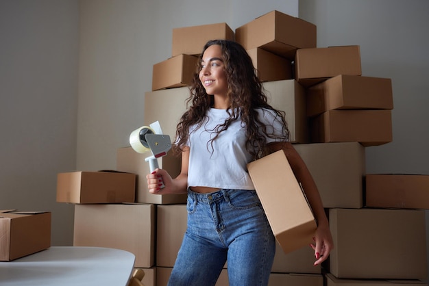 Gelukkige vrouw die de container thuis uitpakt en de kartonnen doos opent die in het pakket kijkt Glimlachende tevreden klant die een pakket ontvangt van de bestellingsbezorgservice die de aankoop uitpakt