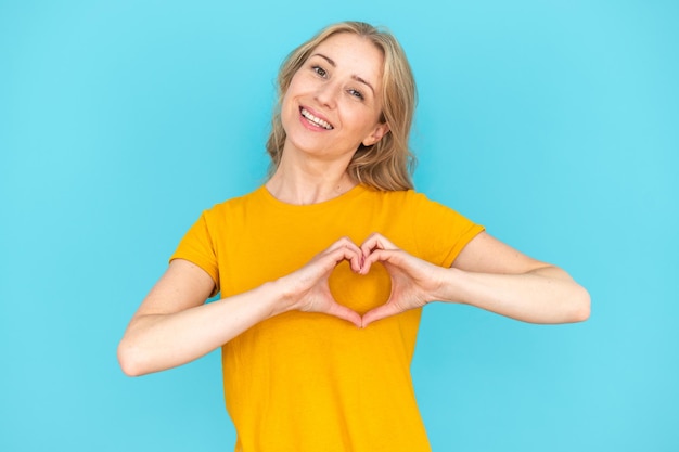 Gelukkige vrouw die een hartvormige gebaar maakt om liefde te tonen