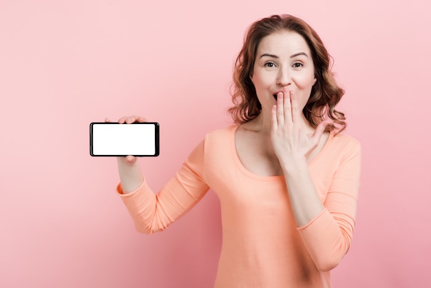 Gelukkige vrouw die een smartphone in haar hand houdt en het lege lege scherm toont