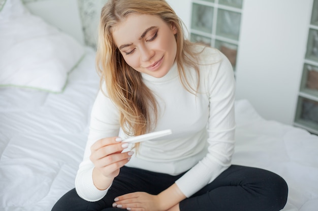 Gelukkige vrouw die een zwangerschapstest bekijkt na resultaat.