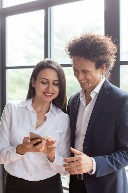 Gelukkige vrouw die foto&#39;s op telefoon tonen aan medewerker