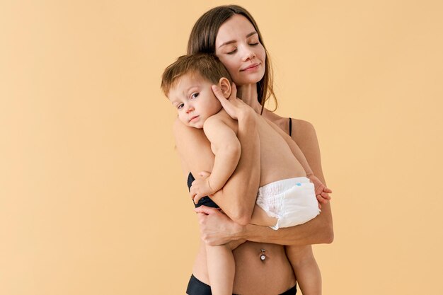 Gelukkige vrouw die haar baby op gekleurde achtergrond houdt