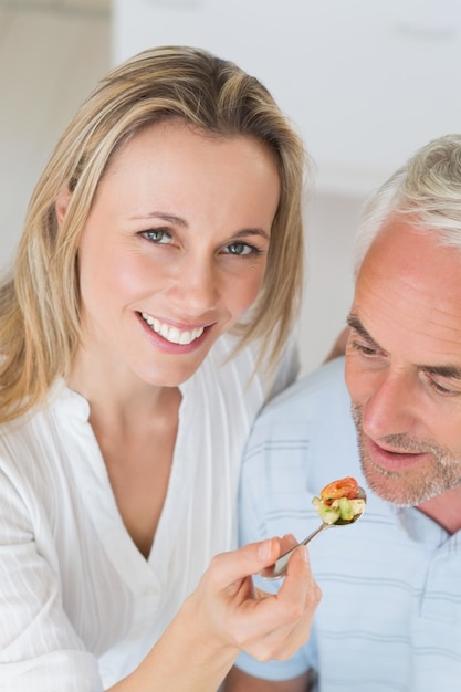 Gelukkige vrouw die haar partner voedt een lepel van groenten