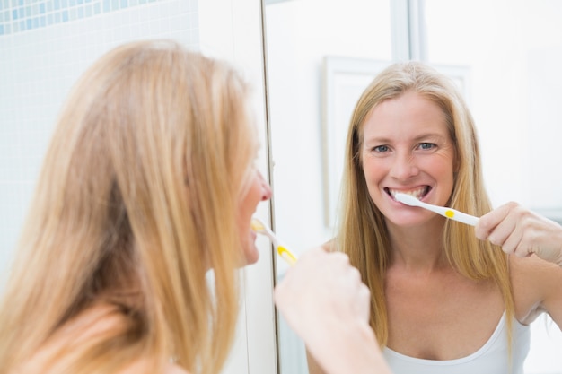 Gelukkige vrouw die haar tanden borstelt