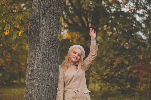 Gelukkige vrouw die hallo zegt op de herfst natuur achtergrond in het herfstpark