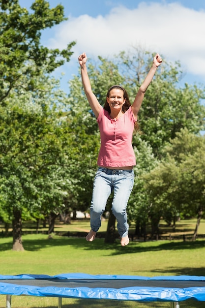 Gelukkige vrouw die hoog op trampoline in park springt