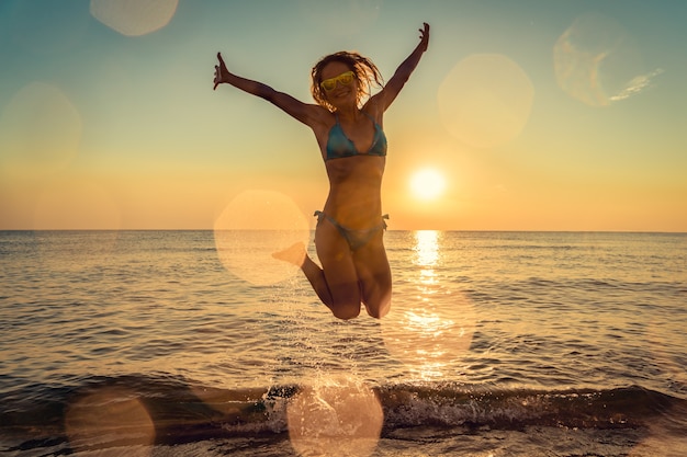 Gelukkige vrouw die in de zee springt Persoon die plezier heeft buiten Zomervakantie en een gezond levensstijlconcept lifestyle