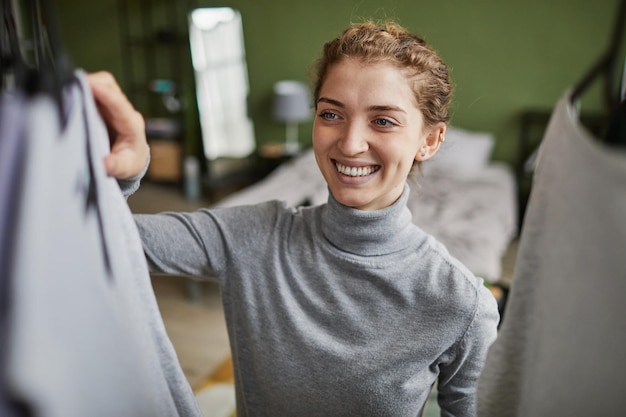 Gelukkige vrouw die kleding kiest voor werk