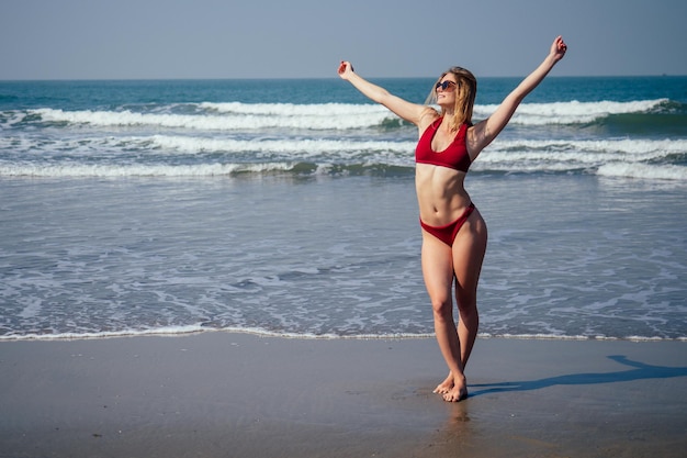 Gelukkige vrouw die lacht en plezier heeft op het strand Zomerportret van een jong mooi meisje in een rode bikini