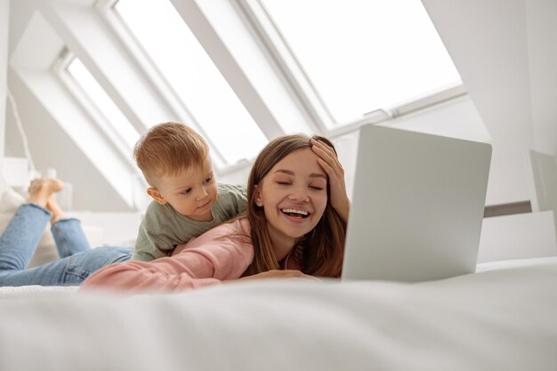 Gelukkige vrouw die laptop gebruikt terwijl ze tijd doorbrengt met haar baby