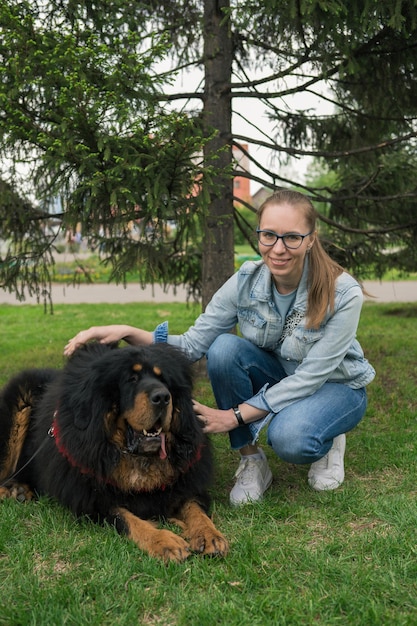 Gelukkige vrouw die met Tibetaanse mastiff in park loopt