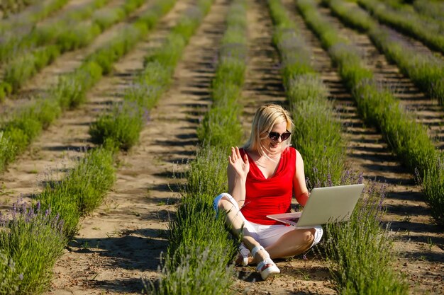 Gelukkige vrouw die online vakanties plant om informatie te zoeken op een laptop in een resort of hotel op het strand