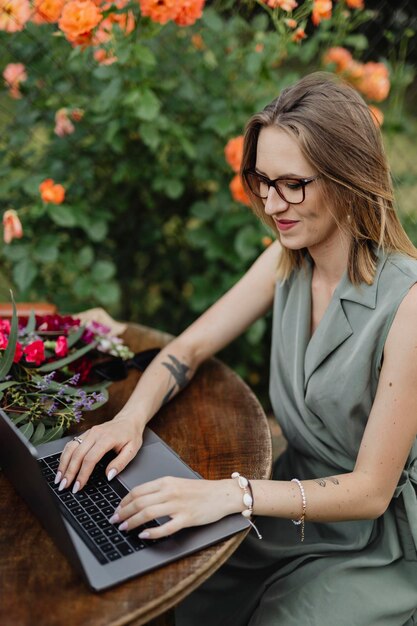 Gelukkige vrouw die op haar laptop in de tuin werkt